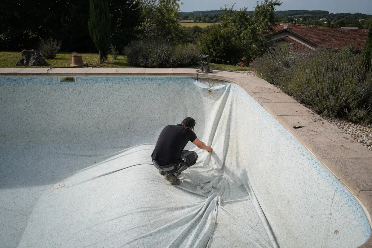 Technicien inspectant le liner plissé d’une piscine enterrée vidée pour diagnostic